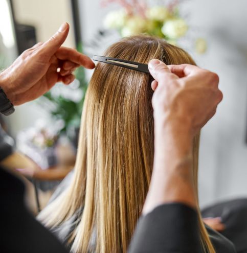 Confident male stylist is dyeing hair of blond caucasian female client